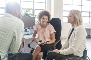 Business professionals in office - two young women and a man - one woman is wheelchair user