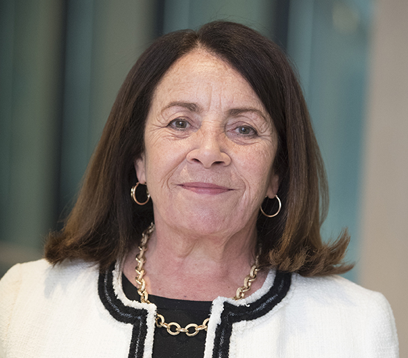 Middle aged woman with shoulder length brown hair smiles at camera