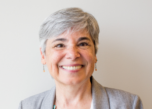 Middle aged woman with short gray hair smiles at camera