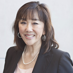 Middle aged Asian women with medium length dark hair smiles at camera