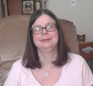 Women with glasses and medium length dark hair smiles at camera