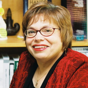 Middle aged woman with short hair and glasses smiling at camera