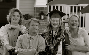 Family - son, father, daughter wearing graduation cap and gown, mother smiling