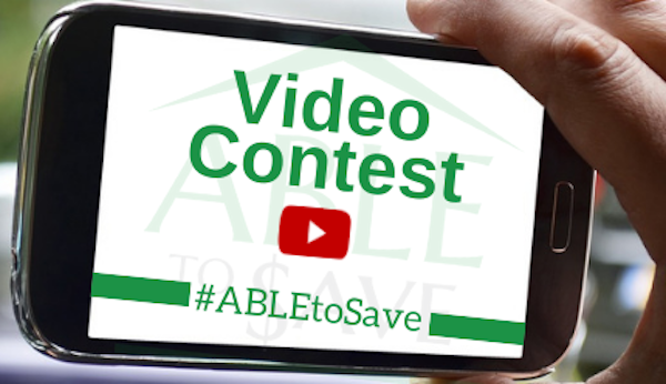 Hand holding cellphone with "Video Contest - #ABLEtoSave" on screen.