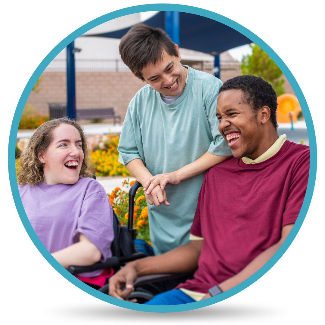 Two men and one woman, with different ethnic backgrounds, laughing together. Two of the individuals are in wheelchairs and one individual has a developmental disability.